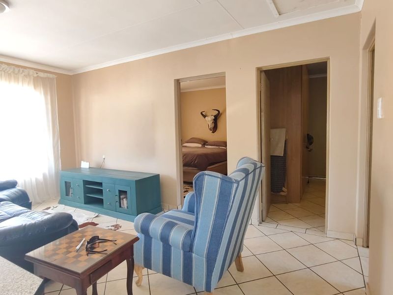 Living area featuring tiled flooring and direct access to adjacent rooms, showing signs of wear on the ceiling finishes.