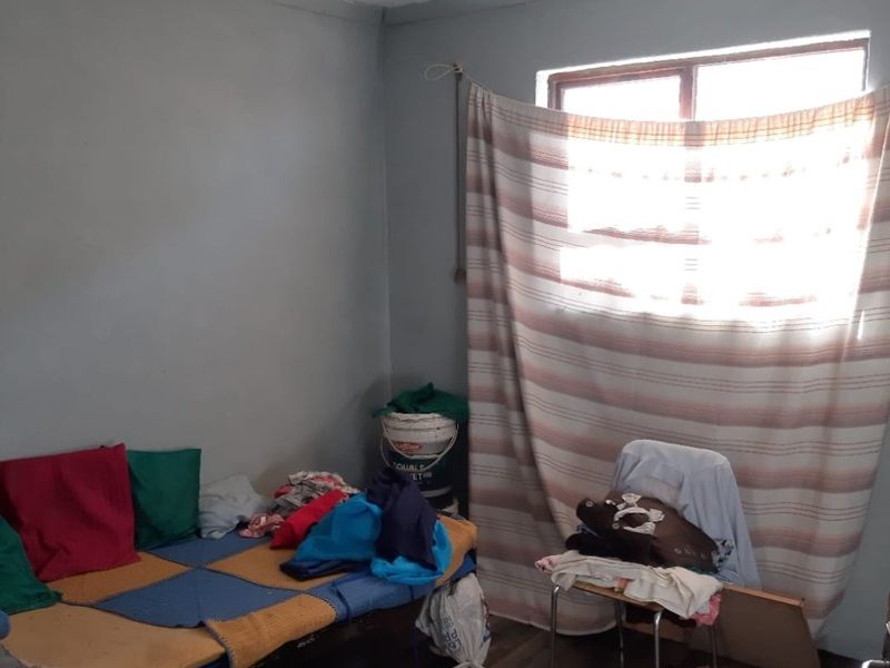 A bedroom space featuring basic wall finishes and a window, requiring cosmetic updates and maintenance to improve the overall condition and appeal.