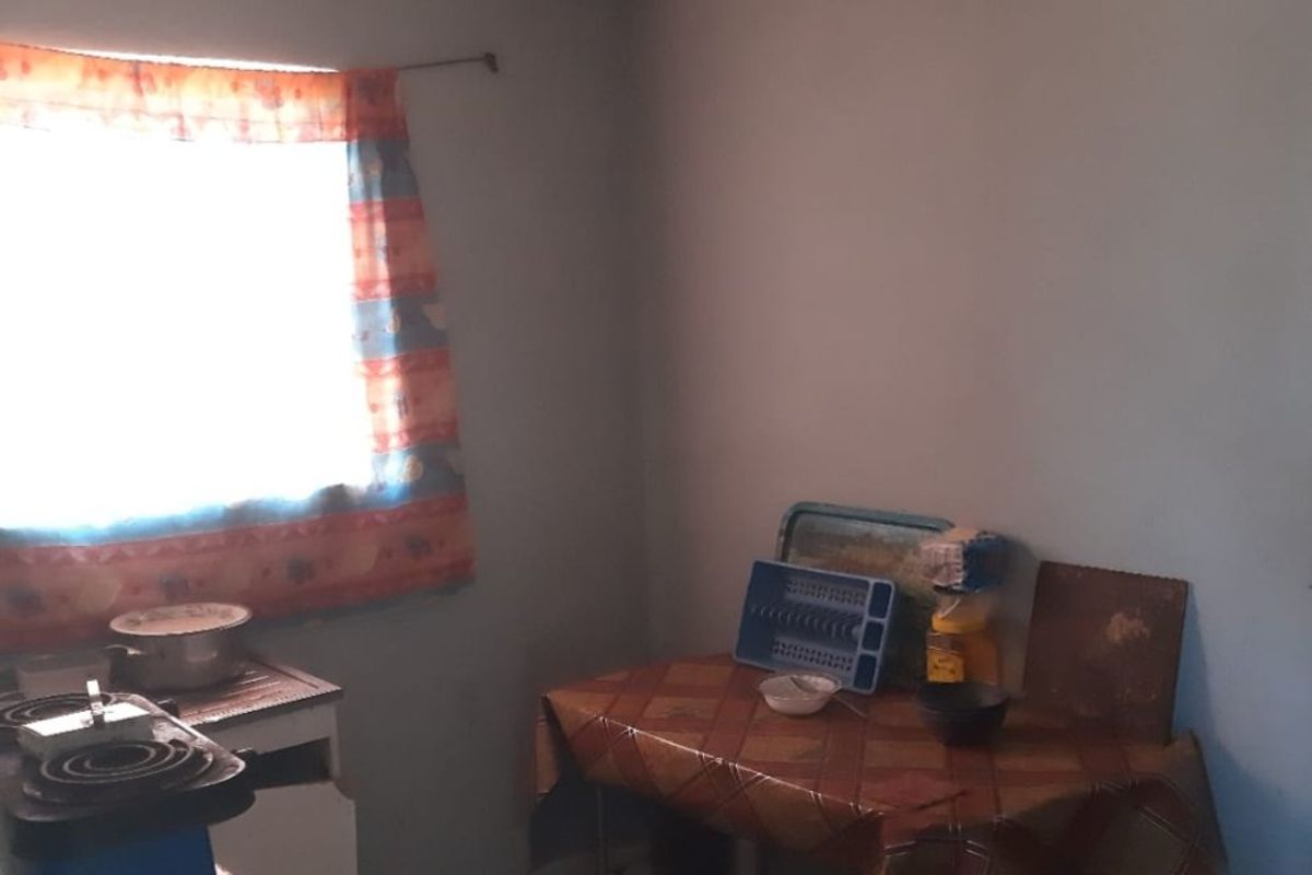 A basic kitchen area featuring tiled flooring and a window, currently lacking built-in cabinetry and requiring significant modernization to improve functionality and aesthetic appeal.