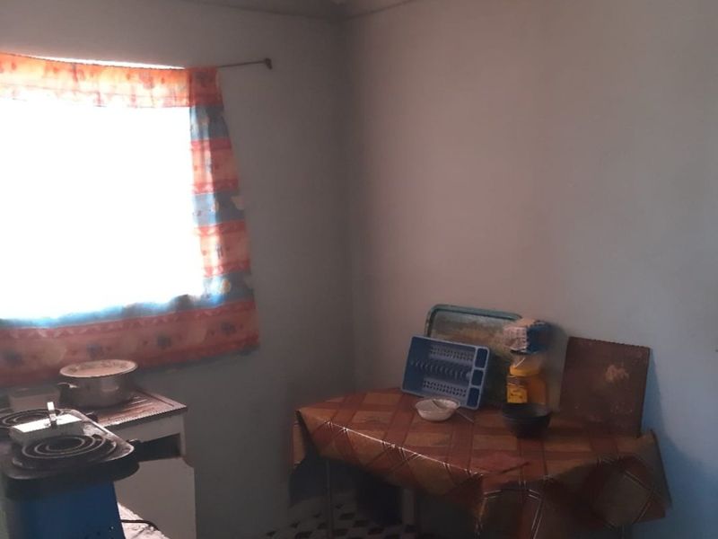 A basic kitchen area featuring tiled flooring and a window, currently lacking built-in cabinetry and requiring significant modernization to improve functionality and aesthetic appeal.