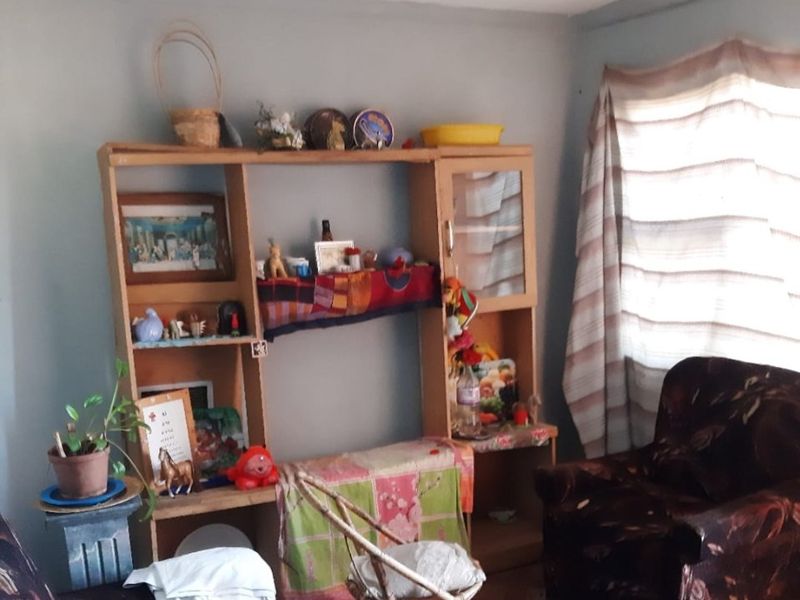 A living room area featuring tiled flooring and natural light from a window, currently requiring cosmetic updates to improve the overall aesthetic.