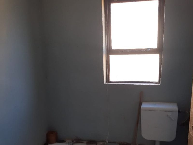 A dated bathroom featuring a standard bathtub and toilet with exposed plumbing, requiring renovation to modernize the space.