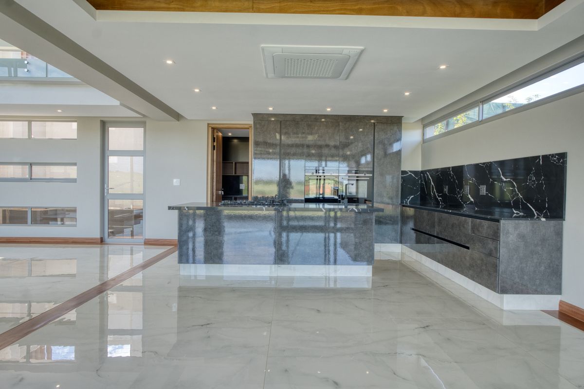 Modern open-plan kitchen featuring high-gloss cabinetry, marble-effect countertops, integrated appliances, and polished porcelain floor tiles.