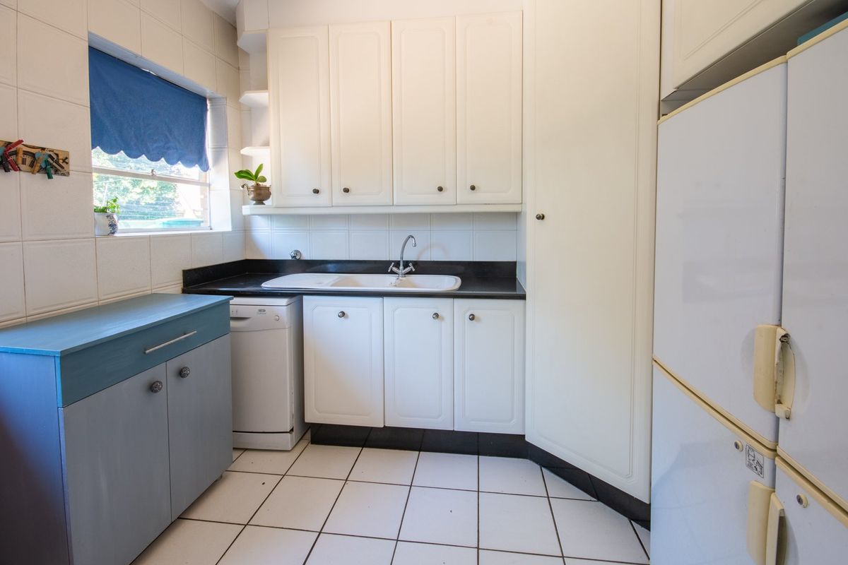 A functional kitchen featuring white cabinetry, a dark countertop, a double sink, and tiled flooring, providing a practical workspace for daily tasks.