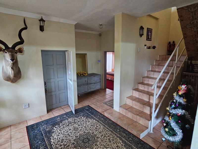 Entrance hall featuring tiled flooring, a staircase with metal railing, and access to adjacent living areas.