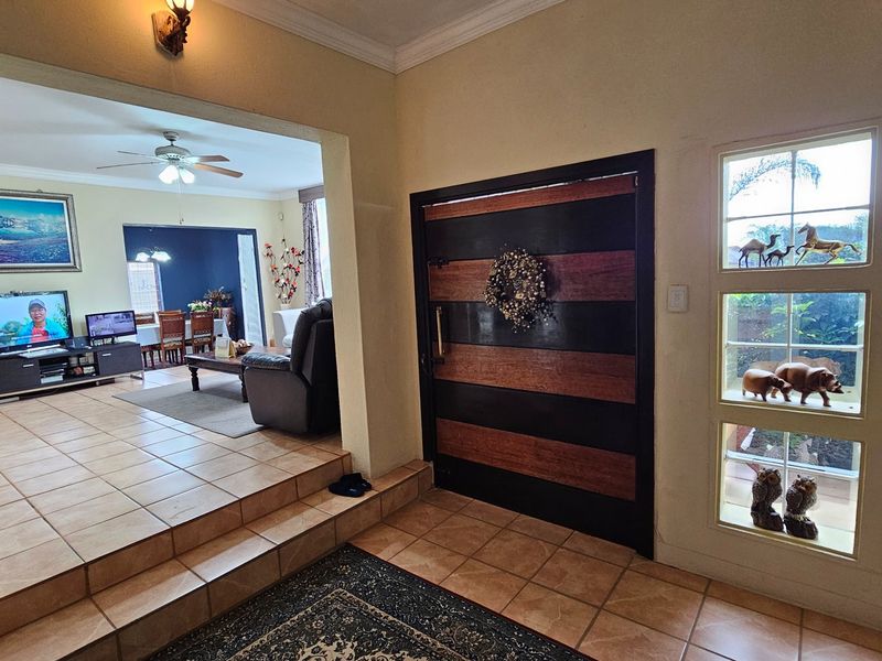 Entrance foyer featuring tiled flooring and a distinctive horizontal-paneled wooden front door, leading into an open-plan living and dining area.