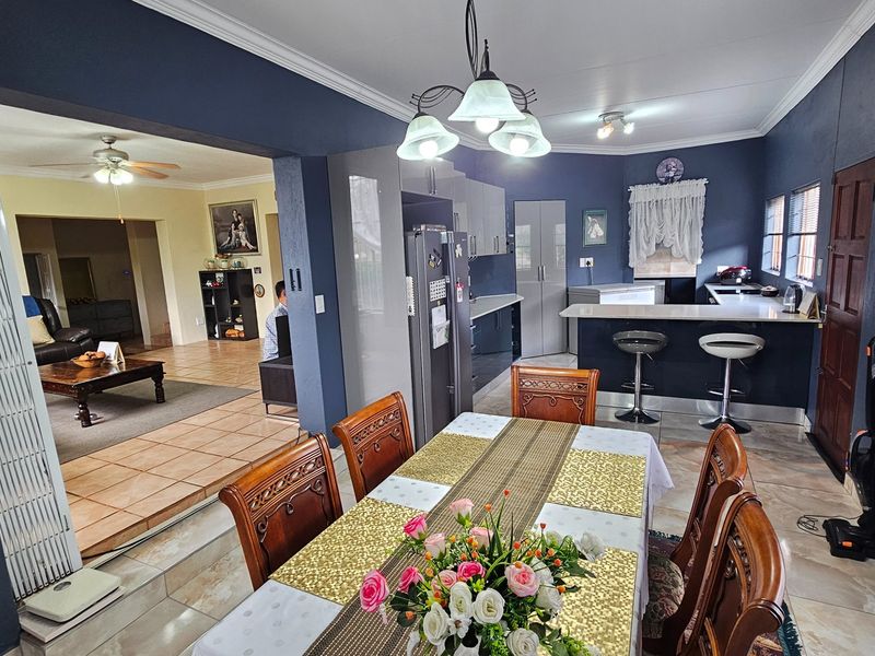 Open-plan dining and kitchen area featuring a breakfast bar, modern cabinetry, and tiled flooring, seamlessly connecting to the adjacent living room.