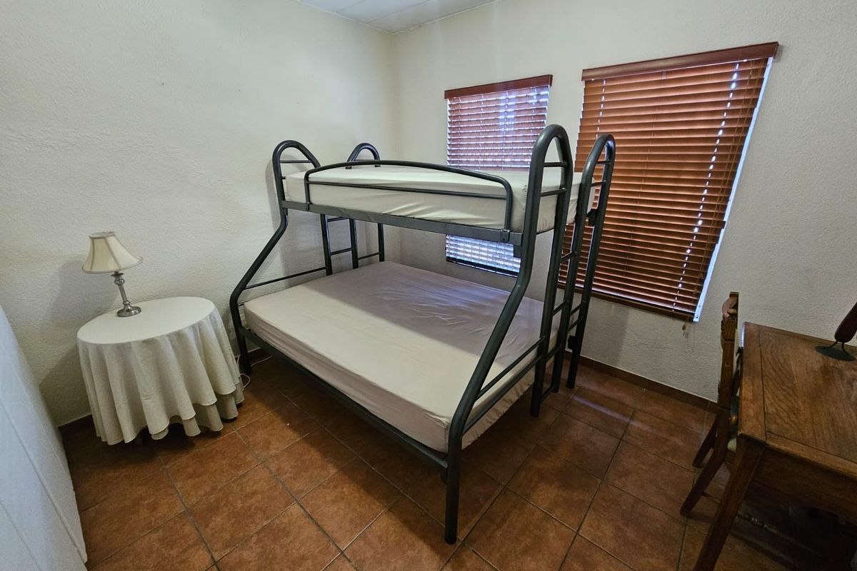 A functional bedroom featuring tiled flooring and wooden venetian blinds, providing a neutral base for potential interior updates.