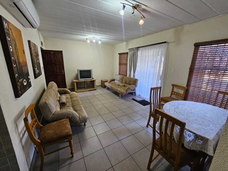 Open plan living and dining area featuring tiled flooring, air conditioning, and sliding door access to the exterior.