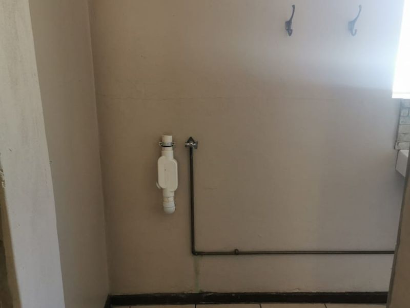 A functional laundry area featuring tiled flooring and dedicated plumbing connections for washing appliances.