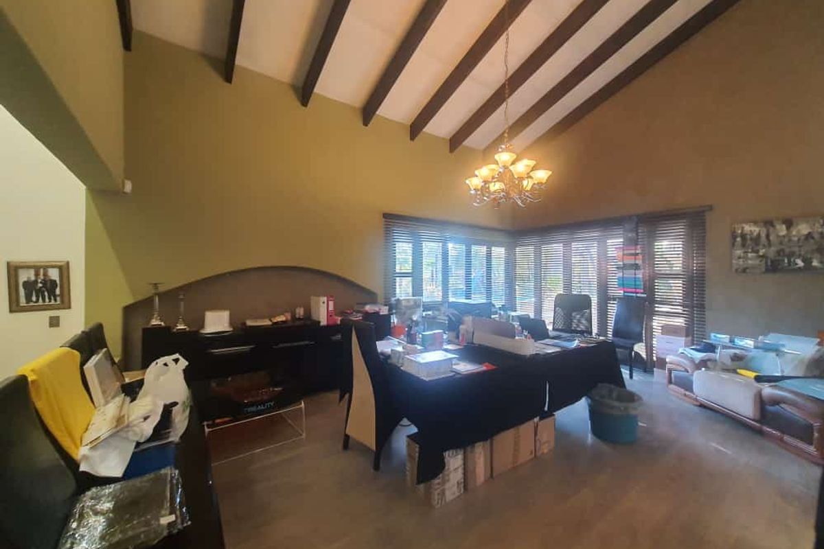 Spacious living area featuring high vaulted ceilings with exposed timber beams, large windows with blinds, and tiled flooring.