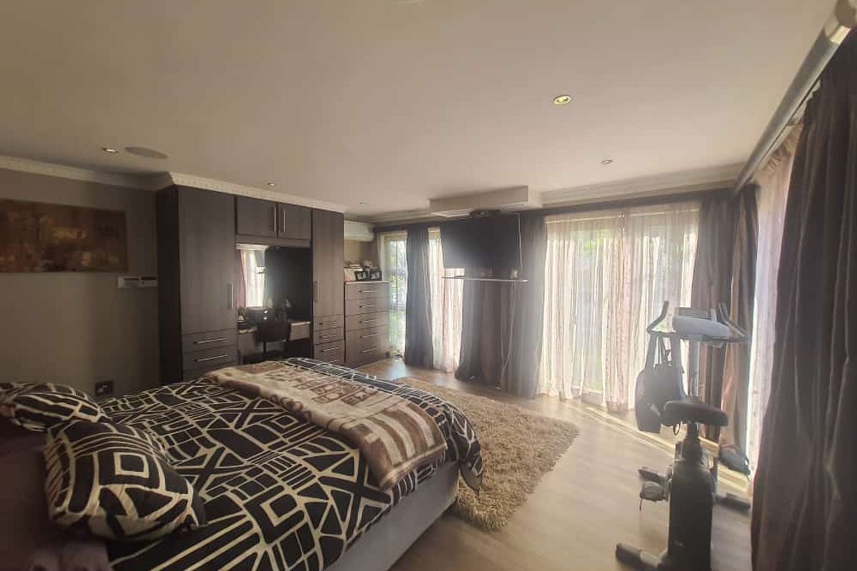 Spacious bedroom featuring built-in dark wood cabinetry, recessed ceiling lighting, and large sliding glass doors providing access to the exterior.
