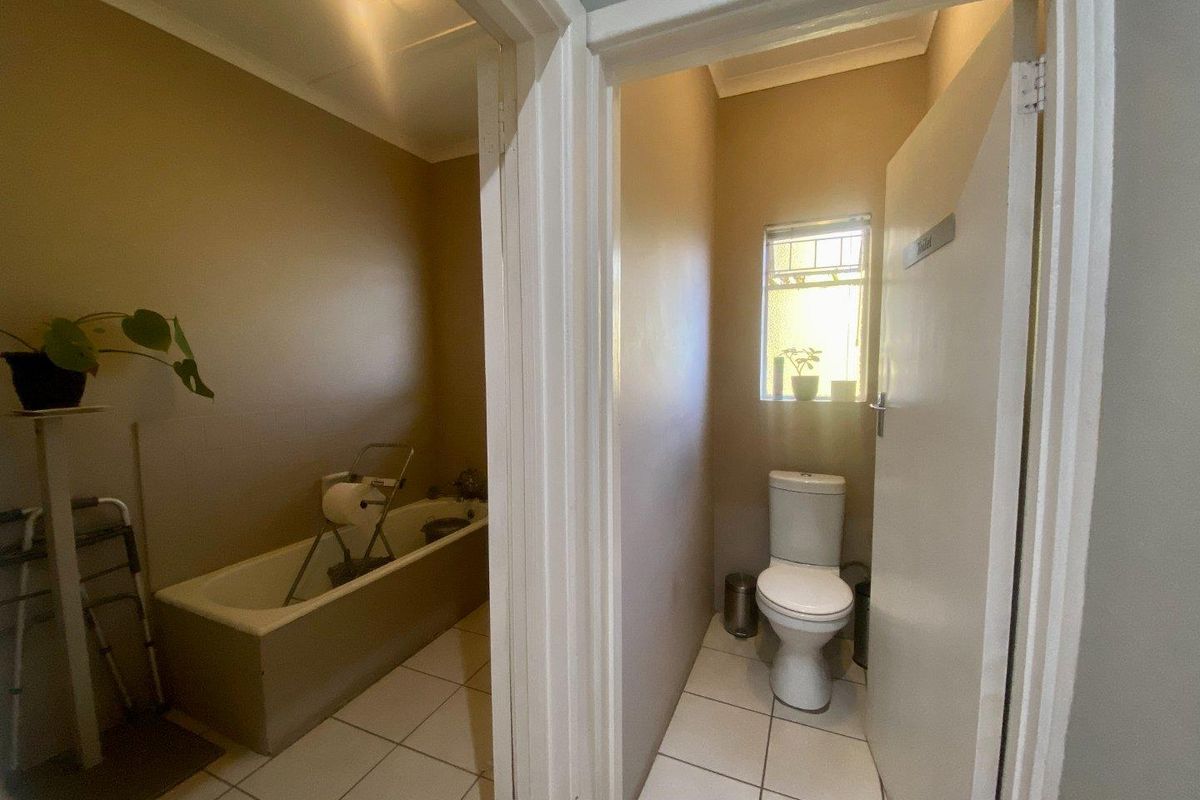 A functional bathroom area featuring a separate toilet room and a bathtub, finished with tiled flooring and neutral wall tones.