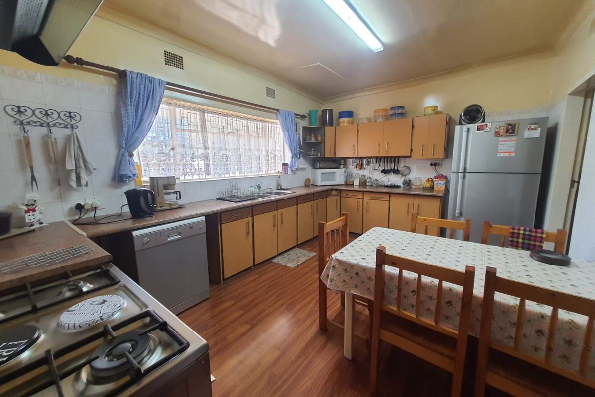 A functional kitchen featuring wooden cabinetry, laminate countertops, a gas hob, and an integrated sink, with space for a dining table.