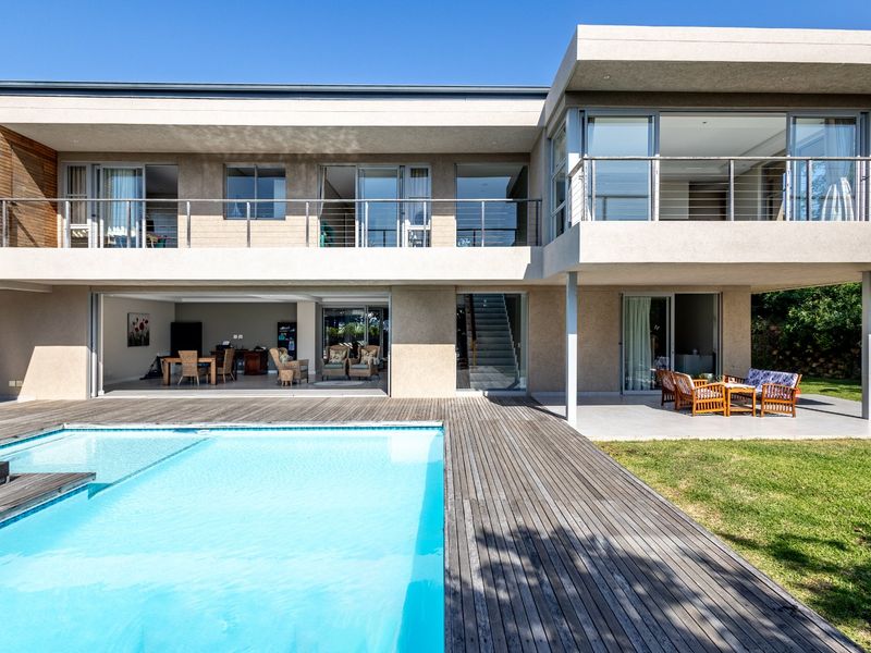 Modern double-story residence featuring a swimming pool, expansive timber decking, and a covered patio area with seamless indoor-outdoor flow.