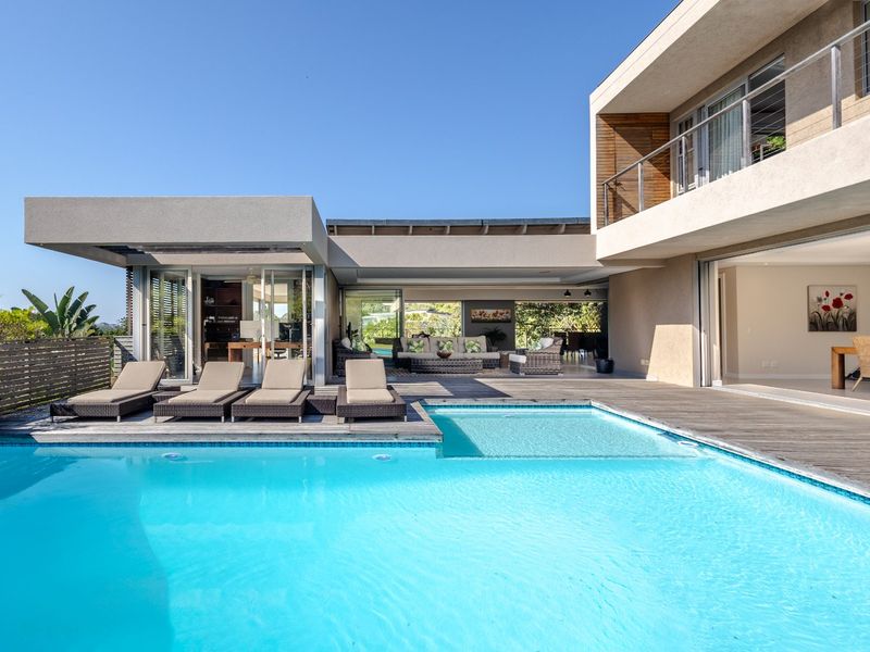 Modern outdoor living area featuring a swimming pool, expansive timber decking, and seamless indoor-outdoor flow through large sliding glass doors.