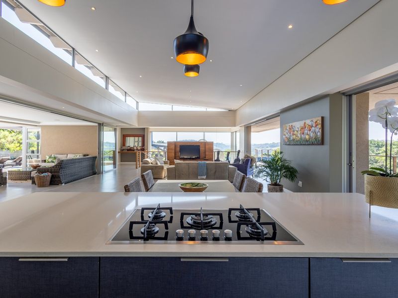 Spacious open-plan living area featuring a modern kitchen island with a built-in gas hob, flowing seamlessly into the dining and lounge spaces.