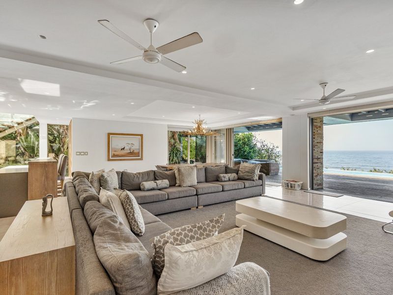 Spacious open-plan living area featuring recessed lighting, ceiling fans, and large sliding glass doors that open to a deck with ocean views.