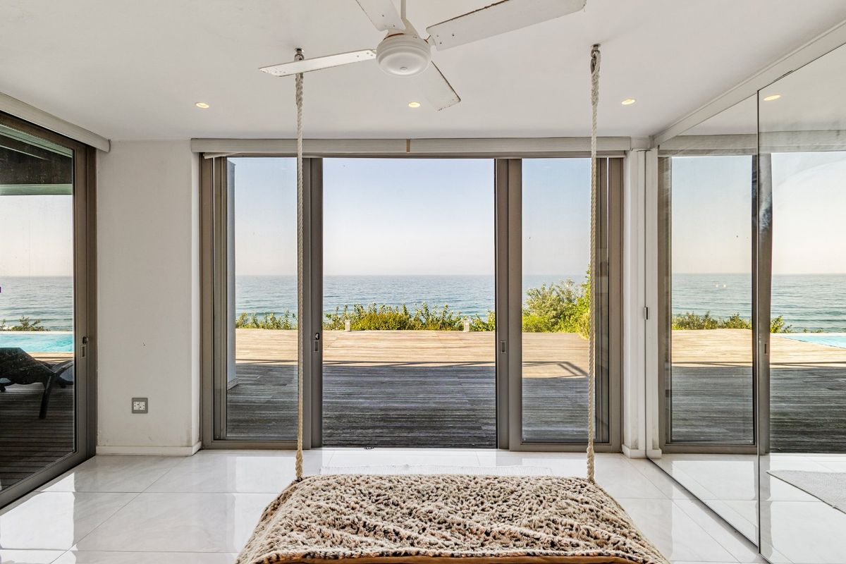 Bright living area featuring large sliding glass doors that open onto a wooden deck with expansive ocean views.
