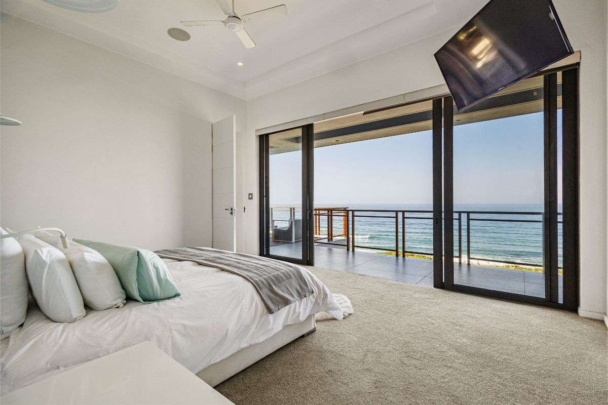 Spacious bedroom featuring large sliding glass doors that open onto a private balcony with expansive ocean views.