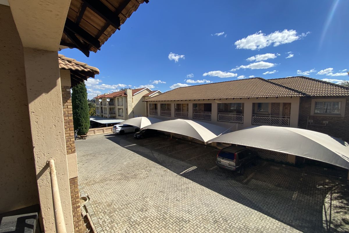 An elevated view of the complex parking area featuring paved driveway and multiple shade-cloth carports for residents.