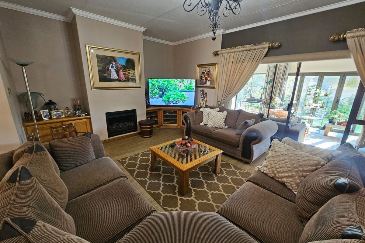 A comfortable living room featuring a built-in fireplace, crown molding, and large sliding glass doors that provide access to the outdoor patio area.