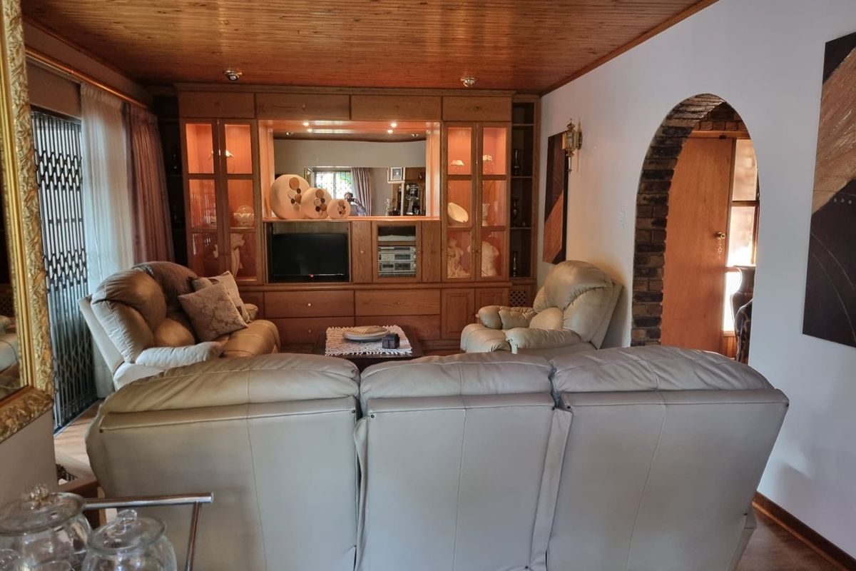 A living room featuring a large built-in wooden wall unit, timber-clad ceiling, and a distinctive brick-arched doorway leading to an adjacent space.