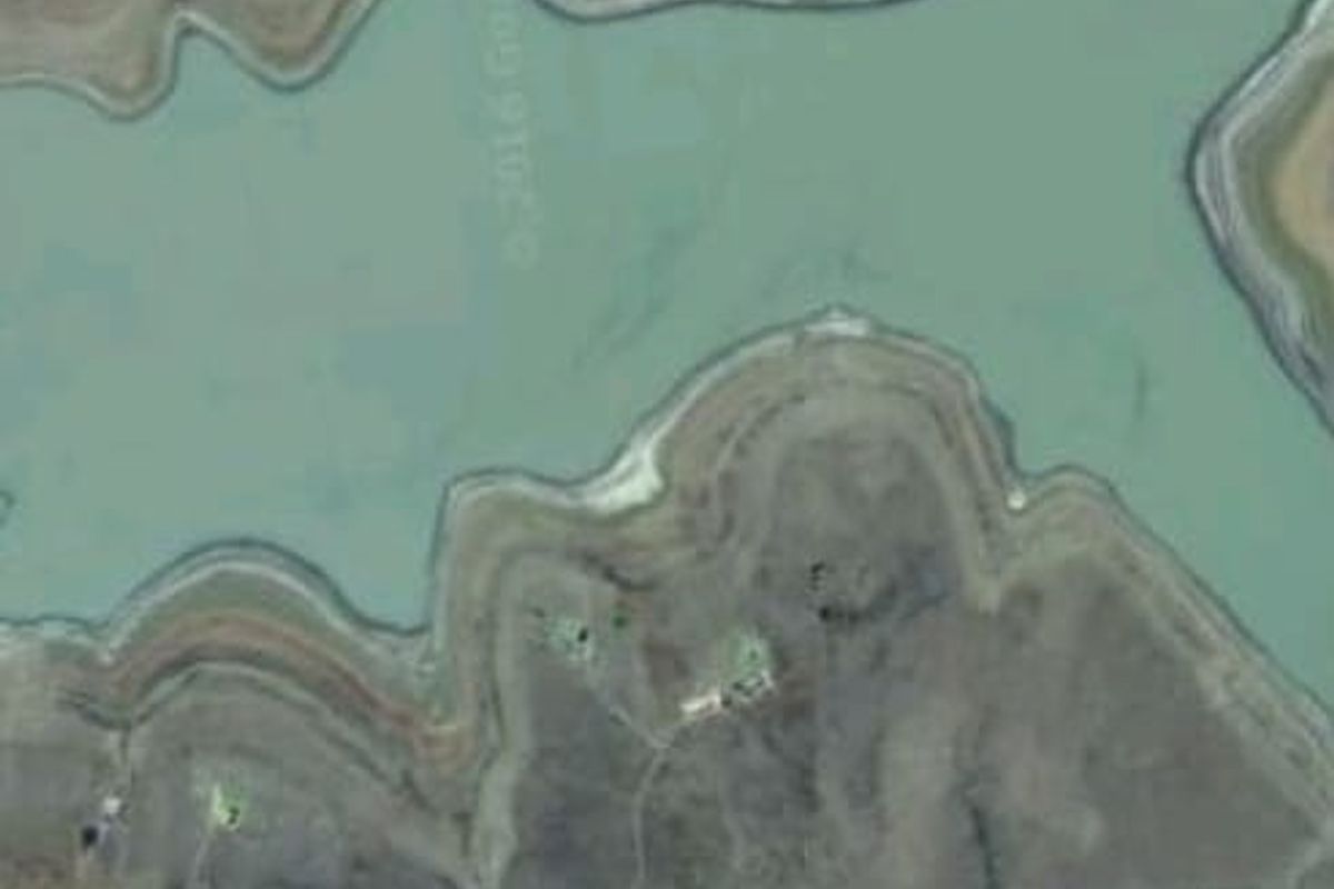 Aerial view of vacant residential land situated along a natural water body, showcasing the surrounding landscape and topography.