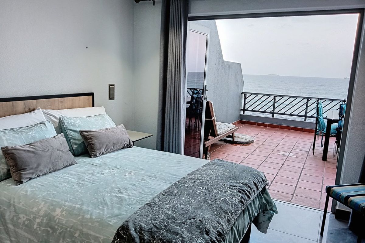 Bedroom featuring a sliding glass door that opens onto a private balcony with ocean views and tiled flooring.