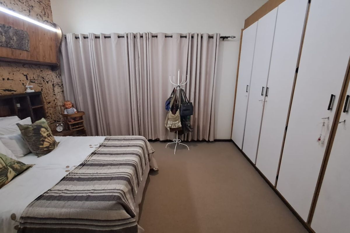 A spacious bedroom featuring built-in floor-to-ceiling wardrobes, carpeted flooring, and a decorative textured feature wall behind the bed area.