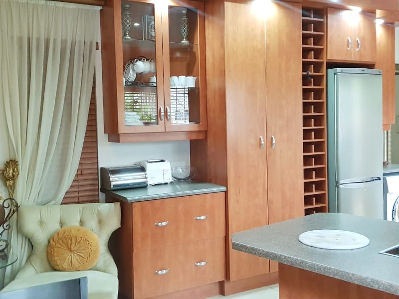 A functional kitchen featuring warm-toned wooden cabinetry, ample storage with a built-in wine rack, and a central island with an integrated hob.