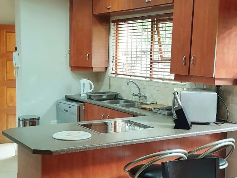 Open plan kitchen featuring wooden cabinetry, laminate countertops, and a breakfast bar, seamlessly integrated with the dining area.