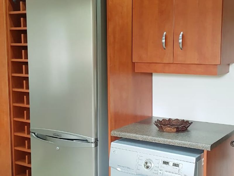 A functional kitchen area featuring warm-toned built-in cabinetry, a dedicated wine rack, stone countertops, and integrated space for appliances.