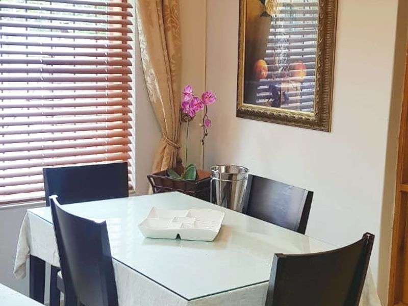 A functional dining area featuring tiled flooring and venetian blinds, providing a neutral space suitable for family meals.