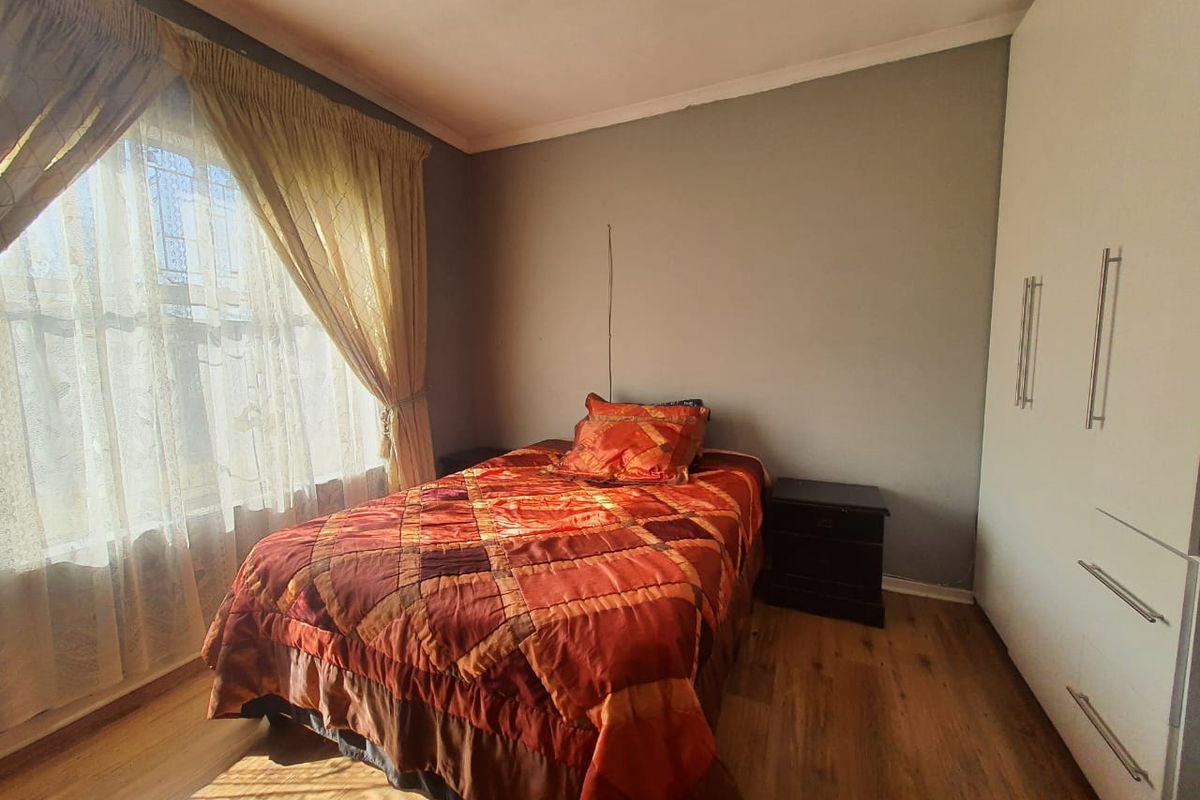 A bedroom featuring built-in wardrobes and wood-look flooring, offering a functional space with natural light.