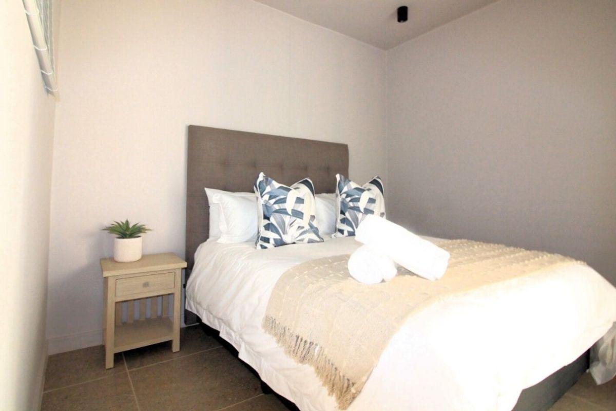 A clean and well-maintained bedroom featuring neutral wall tones, tiled flooring, and a modern recessed ceiling light fixture.