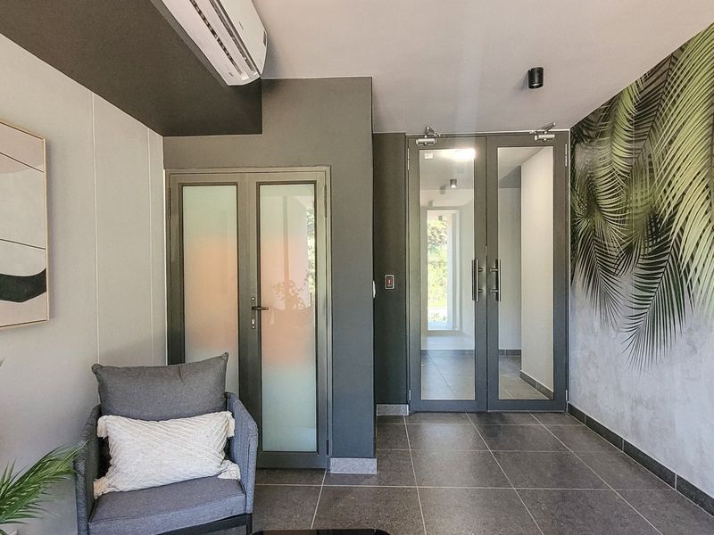 Modern entrance foyer featuring tiled flooring, glass panel doors, and a split-system air conditioner, creating a welcoming and well-maintained transition space.