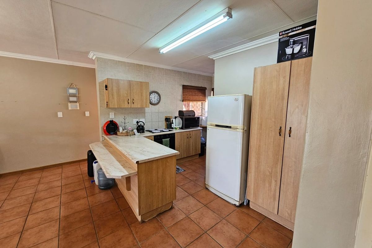 Functional kitchen featuring light wood cabinetry, a breakfast bar, tiled flooring, and built-in cooking appliances, offering a practical layout for daily meal preparation.