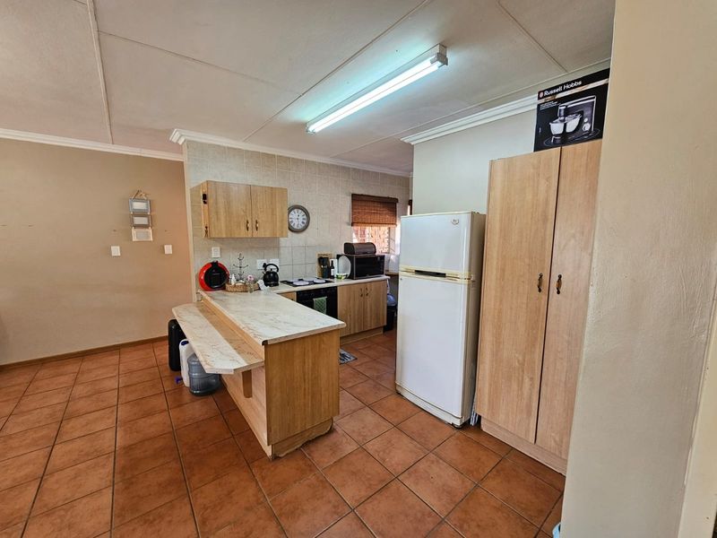 Functional kitchen featuring light wood cabinetry, a breakfast bar, tiled flooring, and built-in cooking appliances, offering a practical layout for daily meal preparation.
