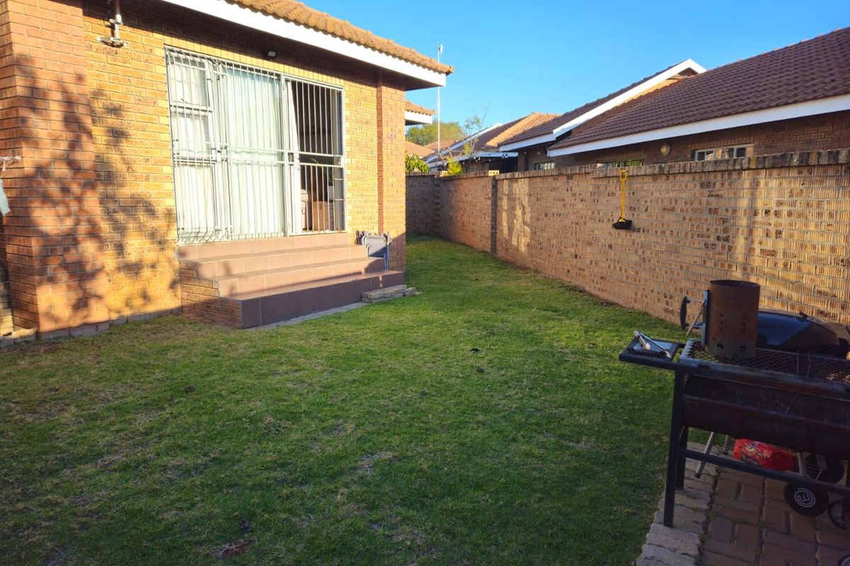 A private rear garden featuring a brick townhouse exterior, tiled patio steps, and a perimeter boundary wall.