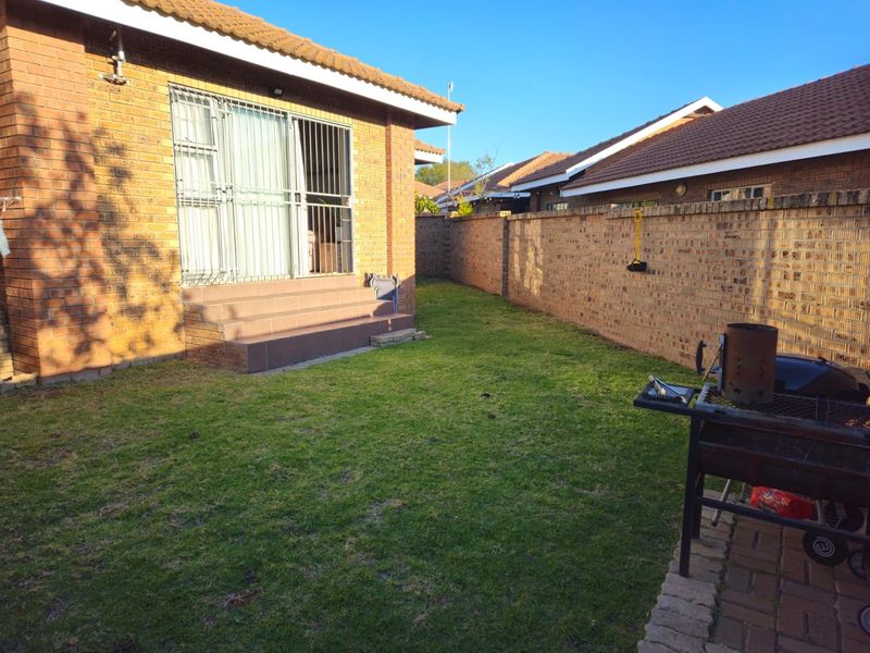 A private rear garden featuring a brick townhouse exterior, tiled patio steps, and a perimeter boundary wall.