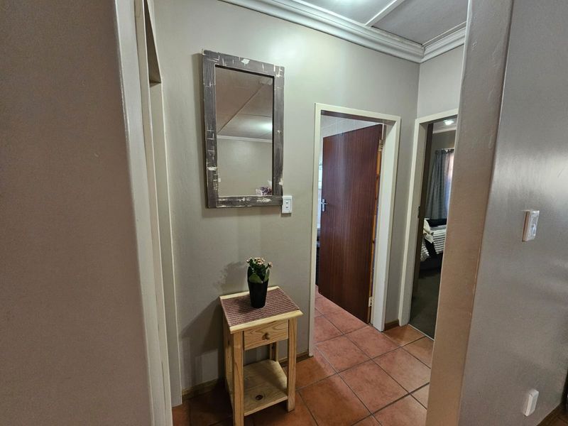A view of a residential hallway featuring tiled flooring and access to adjacent rooms with wooden door frames.