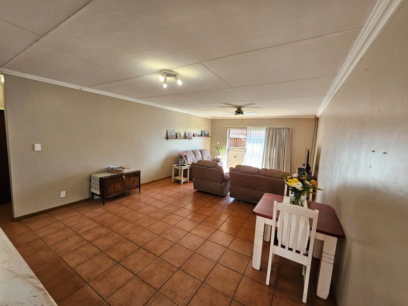 Spacious open-plan living and dining area featuring terracotta floor tiles, neutral wall tones, and sliding door access to the exterior.