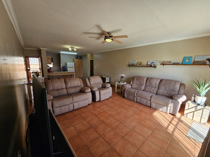 Open plan living area featuring terracotta floor tiles, a ceiling fan, and a seamless flow into the adjacent kitchen space.
