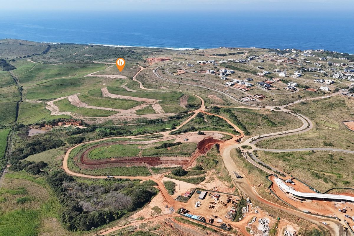 Aerial view of a large residential development site featuring cleared land, graded roads, and coastal proximity.