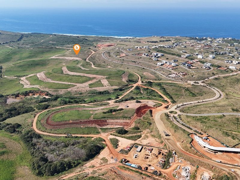 Aerial view of a large residential development site featuring cleared land, graded roads, and coastal proximity.