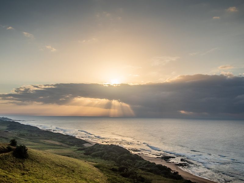 A scenic coastal view overlooking the ocean and shoreline, capturing the natural landscape and horizon at sunset.