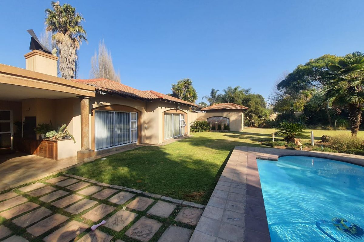 Spacious rear garden featuring a swimming pool, paved patio area, and covered outdoor entertainment space with built-in braai.