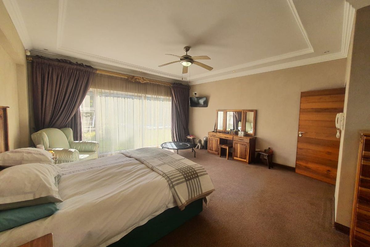 Spacious bedroom featuring a tray ceiling with recessed lighting, a ceiling fan, and large sliding glass doors providing natural light and garden access.