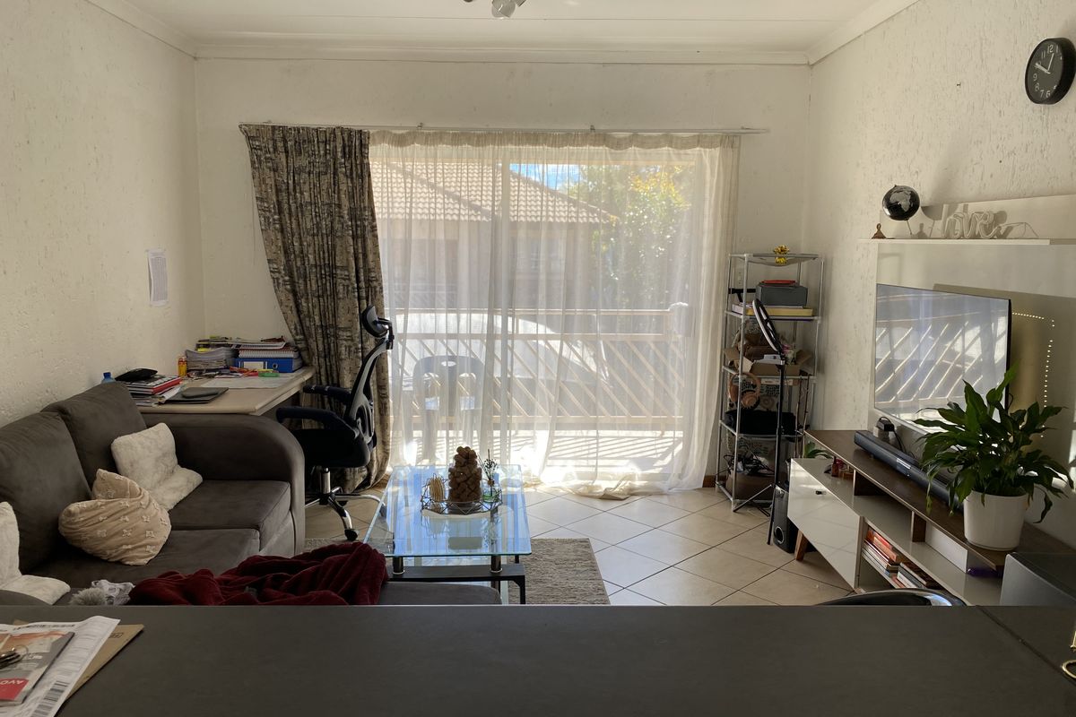 A living room featuring tiled flooring and a sliding glass door leading to a balcony, providing natural light to the space.